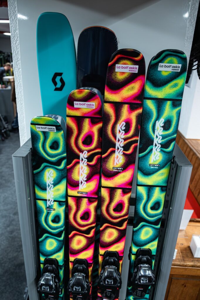 Des skis de location floqués au nom de La Boit'askis, alignés sur leur rack dans le magasin.