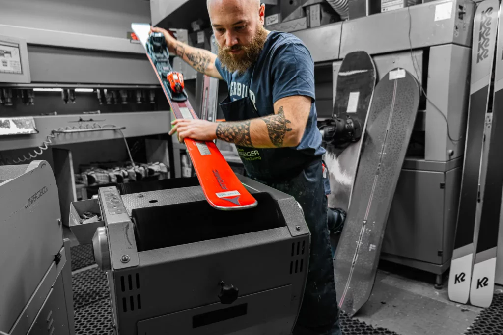 Le skiman de La Boit'askis passe un ski sur la machine de l'atelier.
