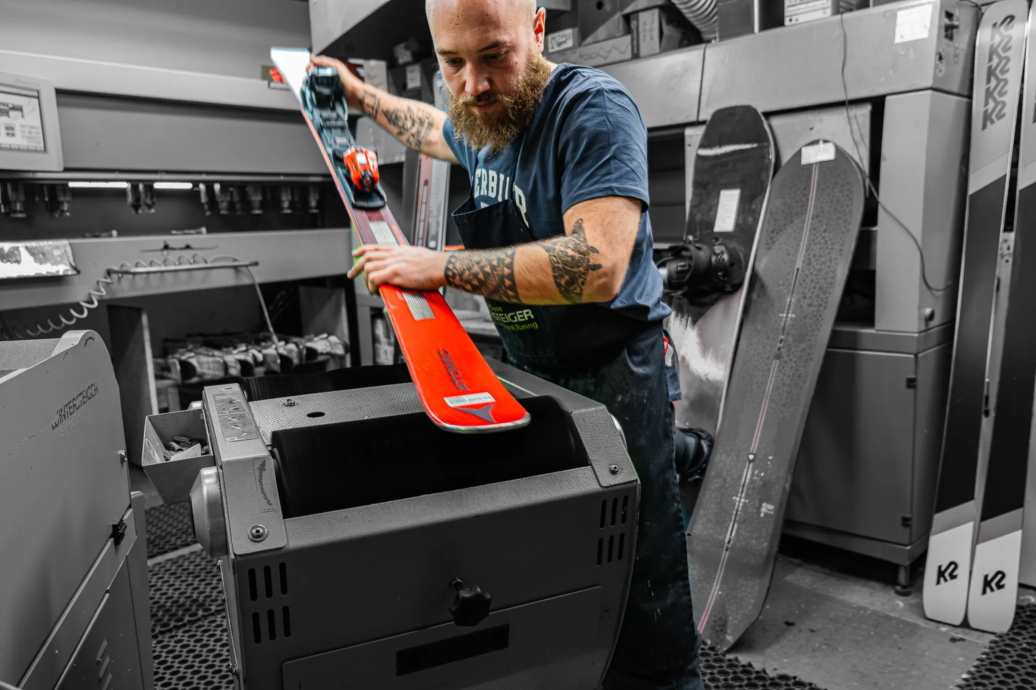 Le skiman de La Boit'askis passe un ski sur la machine de l'atelier.