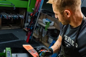 Un technicien de l'atelier révise un ski de location sur la machine.