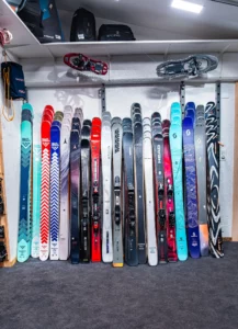 Skis en vente alignés contre le mur, toutes marques.